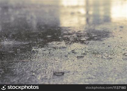 Rain drops in the water heavy on asphalt shade of black shadow and reflection of dark sky in the city. high contrast during autumn
