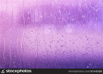 Rain drops on a window in purple colors
