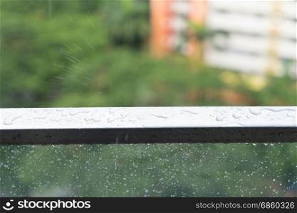 Rain drops on glass balcony, rainy day and apartment in background