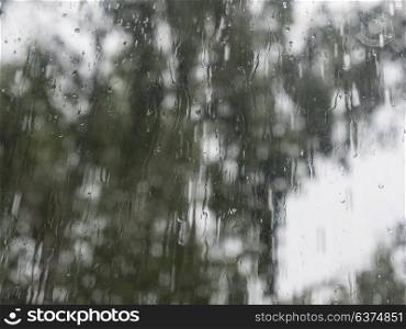Rain drops on window glasses surface with trees against the sky. Rain drops on window glasses surface with trees against the sky.