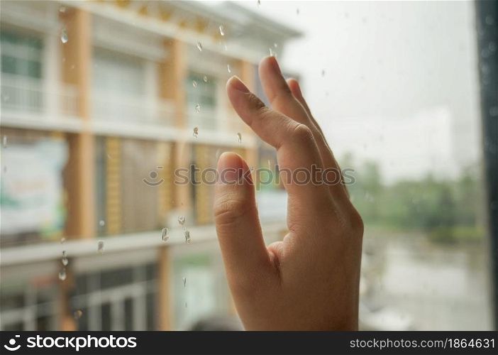 Rain drops on window glasses surface with view rain on glass with hand