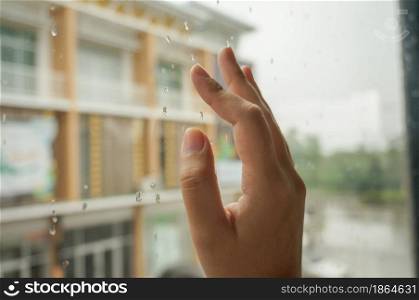 Rain drops on window glasses surface with view rain on glass with hand