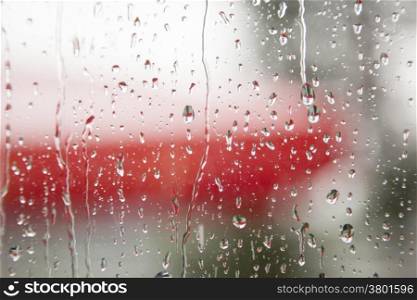 rain on window pane with a lot of red in the background