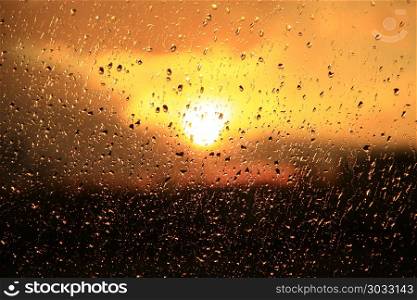 Rain outside window on sunset background. Water drops on glass during raining. Rain outside window on background of sunset. Rain drops on glass during rain. Sunset outside window during raining. Bright texture of water drops