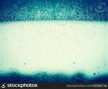 Rain water drops on blue window glass background.