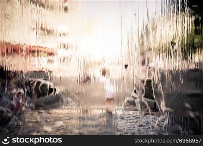 Rain water drops on window glasses surface with urban city life background