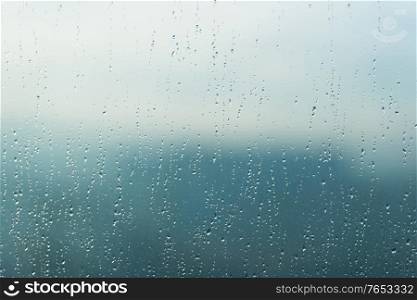 Rain water drops pattern on blue window glass surface