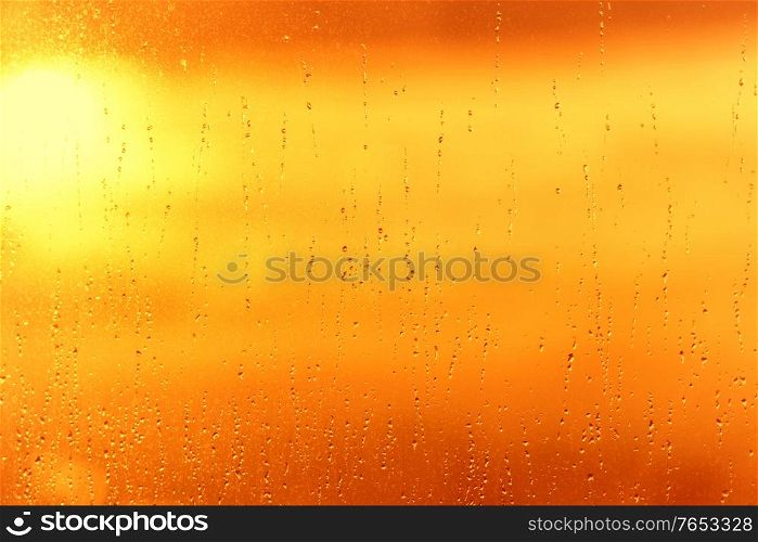 Rain water drops pattern on window glass surface and sunset sky sun