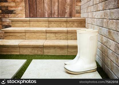 Rain wet rubber boots near porch door. Rain autumn and winter concept