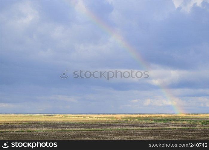 Rainbow, a view of the landscape in the field. Formation of the rainbow after the rain. Refraction of light and expansion in terms of spectra.. Rainbow, a view of the landscape in the field. Formation of the 