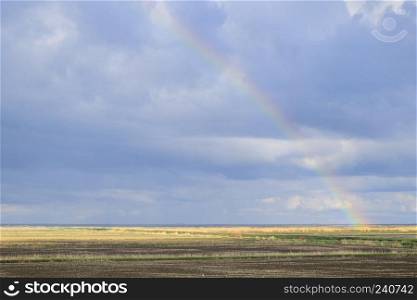 Rainbow, a view of the landscape in the field. Formation of the rainbow after the rain. Refraction of light and expansion in terms of spectra.. Rainbow, a view of the landscape in the field. Formation of the 