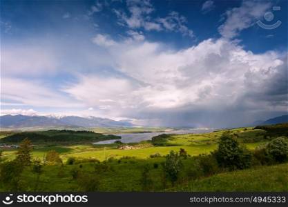 Rainbow after rain. Spring rain and storm in mountains. Green spring hills of Slovakia. Spring stormy scene. Clouds and sunny countryside.