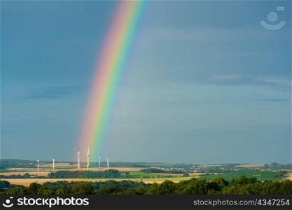 Rainbow and electric windmills in wonderful landscape in summer