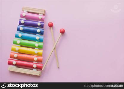 Rainbow Colored Wooden Toy Xylophone on pink bacground. Glockenspiel toy made of metal and wood. Top view. Free space for text. Rainbow Colored Wooden Toy Xylophone on pink bacground. toy glockenspiel made of metal and wood. Copyspace
