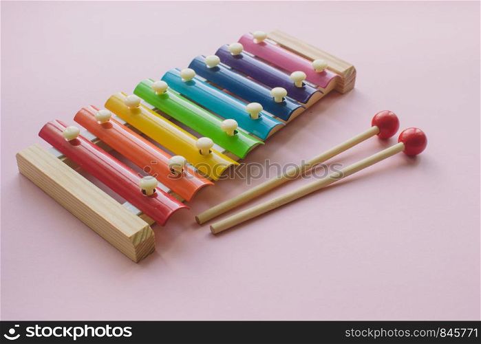 Rainbow Colored Wooden Toy Xylophone on pink bacground. Glockenspiel toy made of metal and wood. Rainbow Colored Wooden Toy Xylophone on pink bacground. toy glockenspiel made of metal and wood
