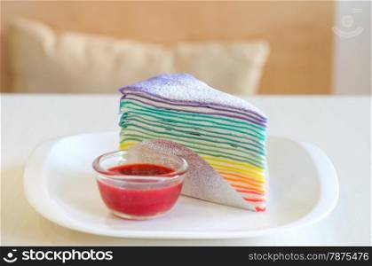 Rainbow crepe cake served with strawberry sauce. Rainbow crepe cake