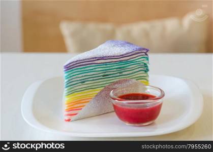 Rainbow crepe cake served with strawberry sauce. Rainbow crepe cake