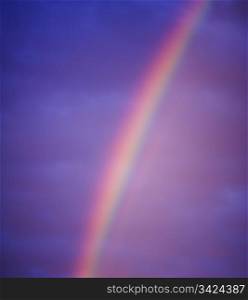 Rainbow in dark clouds emits purple, pink, yellow and green light