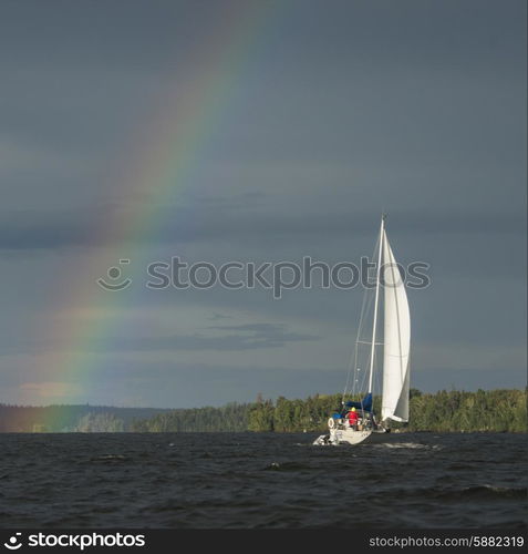 Rainbow over a lake with a sailboat, Lake Of The Woods, Ontario, Canada