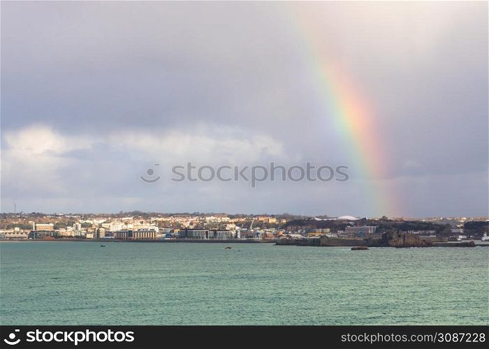 Rainbow over Saint Helier capital city with sea in the foreground, bailiwick of Jersey, Channel Islands, UK
