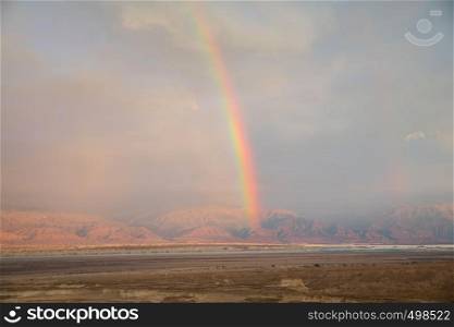 rainbow over the dead sea with jordan as background, view from masada. rainbow over the desert