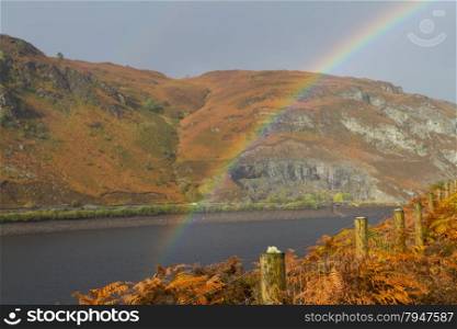 Rainbow over the The Garreg-ddu Reservoir, in mid Wales surrounded by hills. In Autumn or Fall. Elan Valley, Powys, Wales, United Kingdom, Europe.