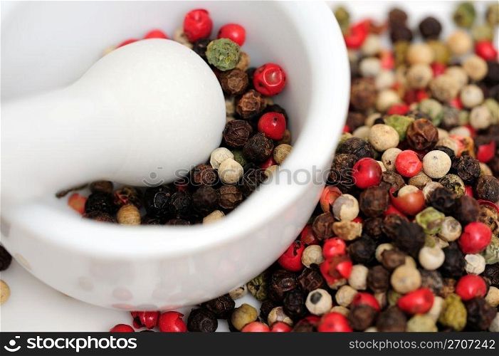Rainbow Peppercorns. Peppercorns in various colors of red, green and the familiar black peppercorn on white with a Mortar and Pestle