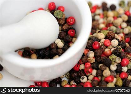 Rainbow Peppercorns. Peppercorns in various colors of red, green and the familiar black peppercorn on white with a Mortar and Pestle