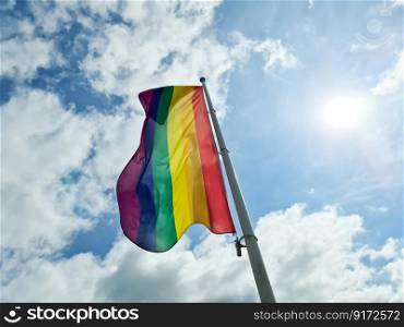 Rainbow pride flag illustration. Lgbt community symbol in rainbow colors against the blue sky 
