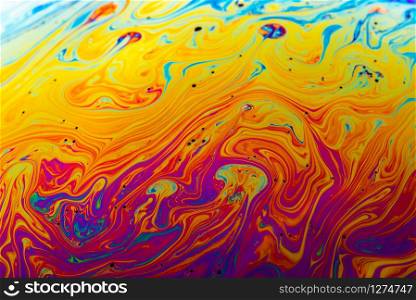 Rainbow soap bubble on a dark background. Close-up of colorful surface.. Abstract background made from soap bubble reflecting light