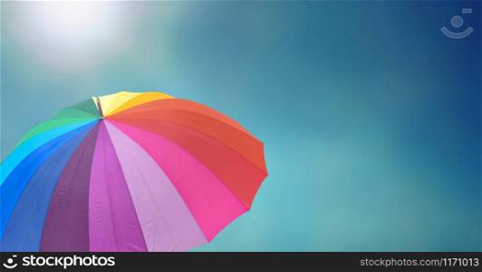 rainbow umbrella under sunny blue sky