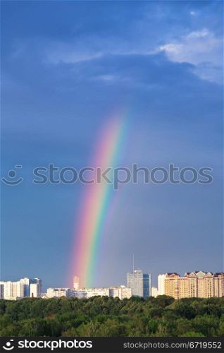 rainbow under city in blue sky