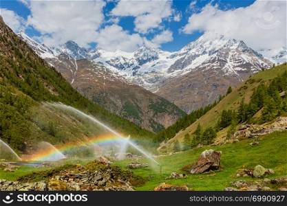 Rainbows in irrigation water spouts in Summer Alps mountain (Switzerland, near Zermatt).