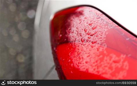 Raindrops on a red car headlight