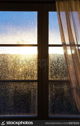 raindrops on a window pane at sunset