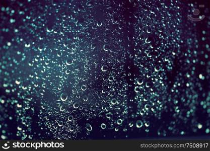 Rainy background, rain drops on the window at night, autumn season backdrop, abstract textured wallpaper