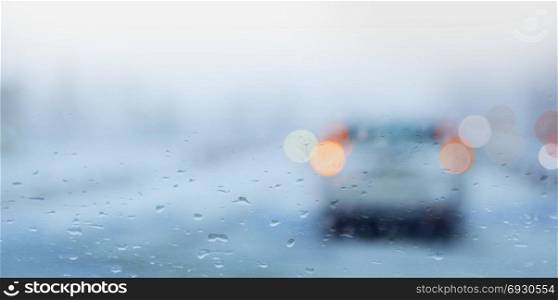 Rainy day, raindrops on the car window with traffic bokeh light
