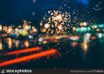 Rainy Evening From The Bus. Drops Of Rain On Blue Glass Background. Street Bokeh Lights Out Of Focus.