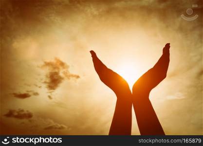 Raised hands catching sun on sunset sky. Concept of spirituality, wellbeing, positive energy etc.. Raised hands catching sun on sunset sky. Concept of spirituality, wellbeing, positive energy