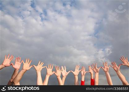 raised hands on cloudy sky background
