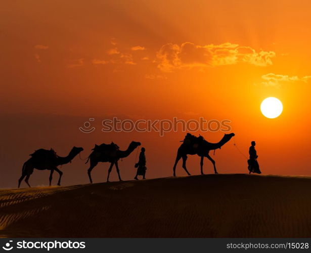 Rajasthan travel background - two indian cameleers (camel drivers) with camels silhouettes in dunes of Thar desert on sunset. Jaisalmer, Rajasthan, India