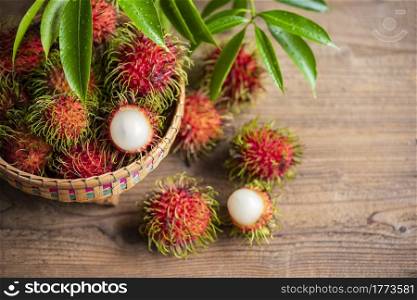 Rambutan fruit on basket and wooden background harvest from the garden, Fresh and ripe rambutan sweet tropical fruit peeled rambutan with leaves