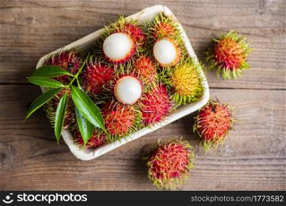 Rambutan fruit on plate and wooden background harvest from the garden, Fresh and ripe rambutan sweet tropical fruit peeled rambutan with leaves