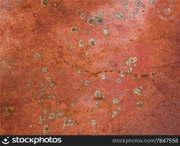 Random patterns of red paint, rust, and lichen on an old abandoned truck result in an abstract, grungy kind of background.