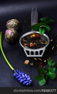 range of exotic teas. Varieties tea infuser spoon with custard on dark background