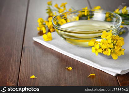 Rapeseed oil with flower of rapeseed. Food composition on wooden table