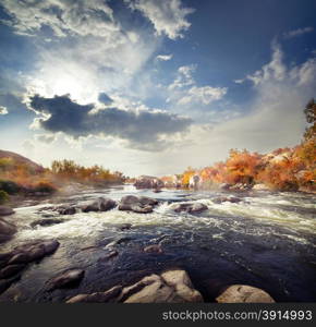 Rapid mountain river among stones and autumn trees