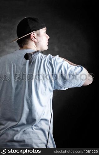 Rapper attitude rap singer hip Hop Dancer performing. Young man with hat microphone back view black grunge background