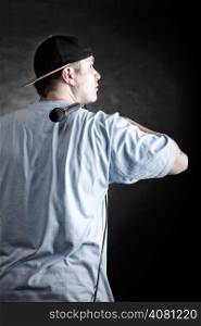 Rapper attitude rap singer hip Hop Dancer performing. Young man with hat microphone back view black grunge background