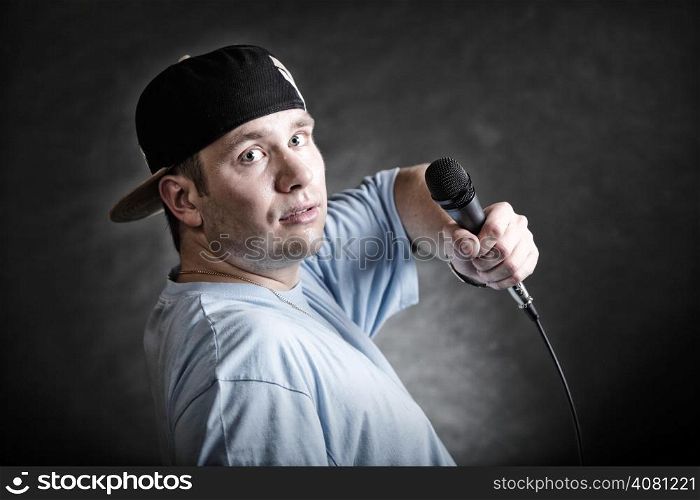 Rapper attitude rap singer hip Hop Dancer performing. Young man with microphone singing black grunge background